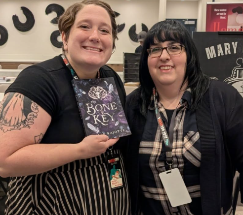 Authors Mallory McCartney and Mary Rajotte. Mallory is holding a paperback copy of The Bone Key written by Mary.
